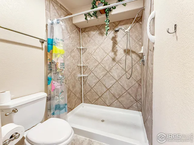 a white toilet sitting next to a bath tub and a shower curtain