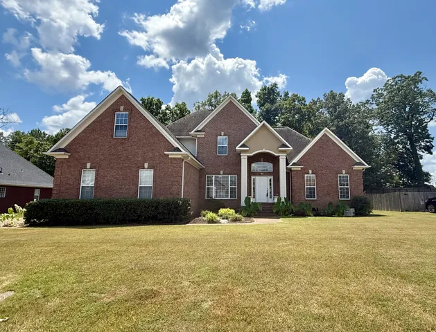 a front view of house with yard and trees around