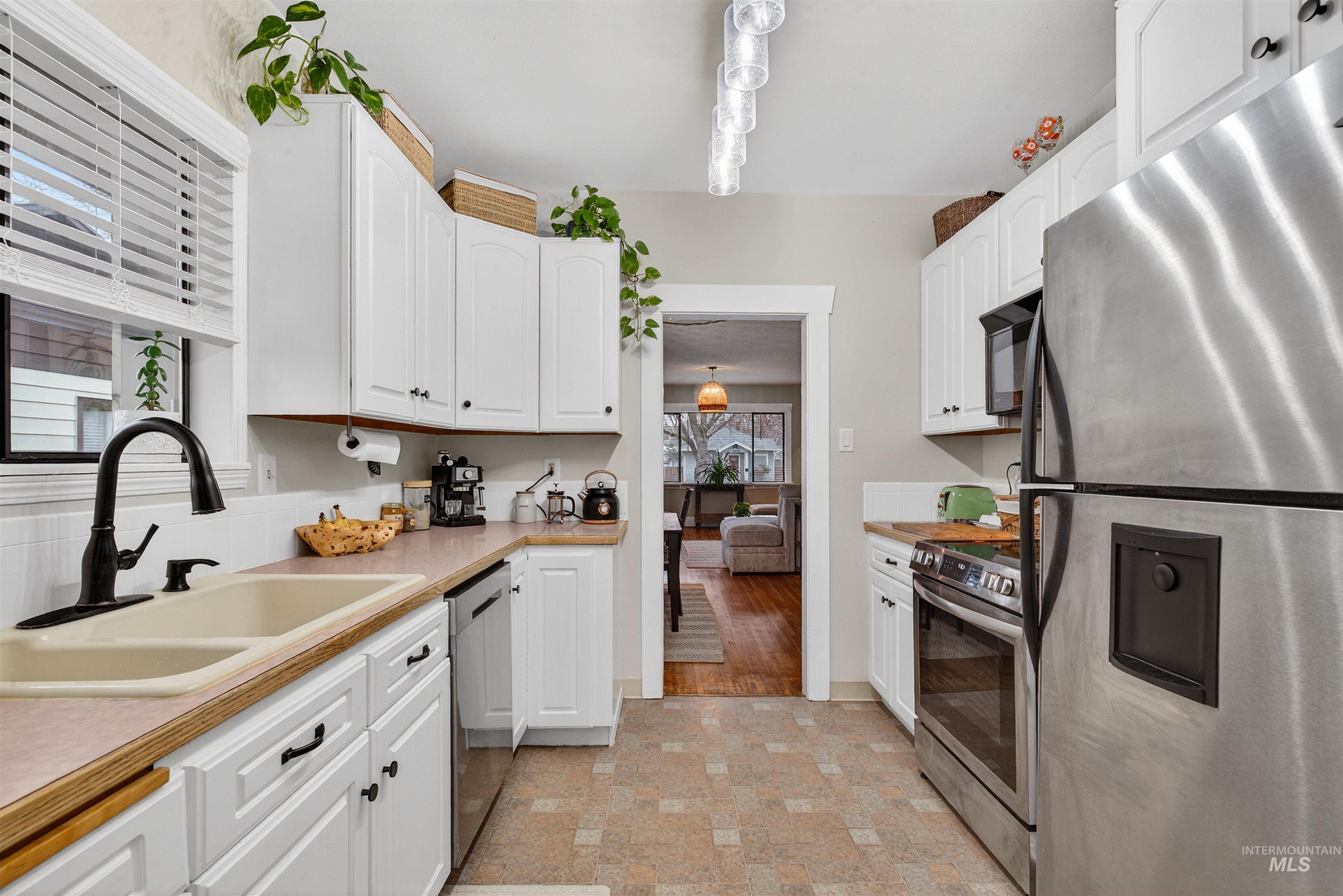 1021 11th Avenue Lewiston, ID 83501 - Photo 12 of 41 Kitchen featuring stainless steel appliances, light countertops, white cabinetry, and decorative light fixtures