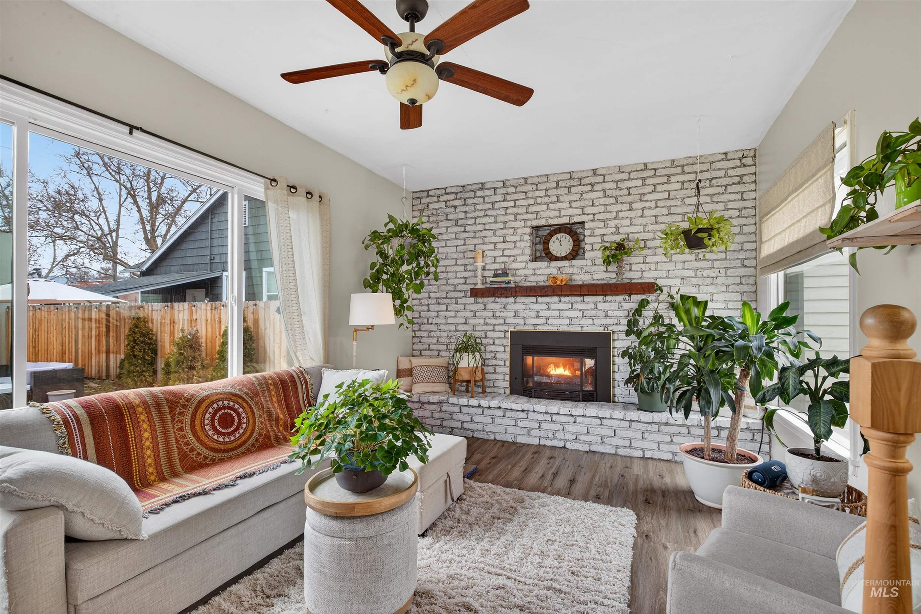 1021 11th Avenue Lewiston, ID 83501 - Photo 13 of 41 Living area with wood finished floors, brick wall, a fireplace, and a ceiling fan