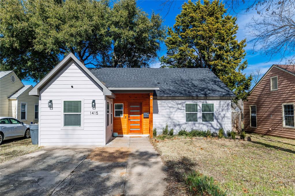 View of front of house with a shingled roof and a front lawn