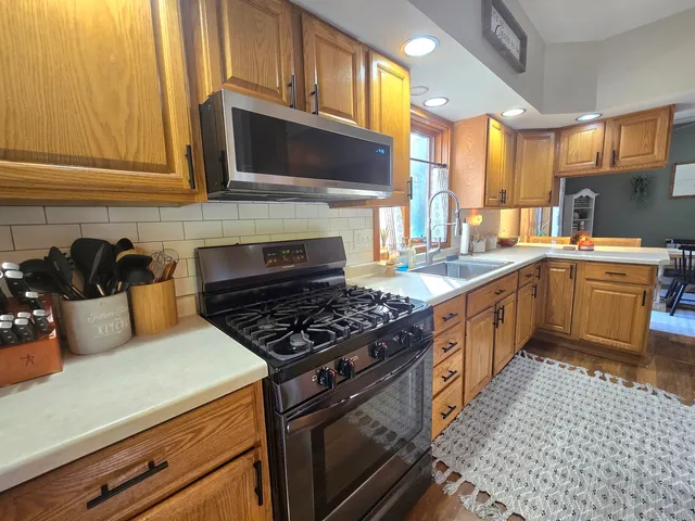 a kitchen with stainless steel appliances a sink a stove a microwave cabinets and a counter top space