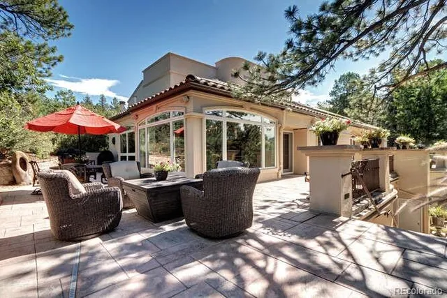 a view of a patio with couches table and chairs under an umbrella with a barbeque