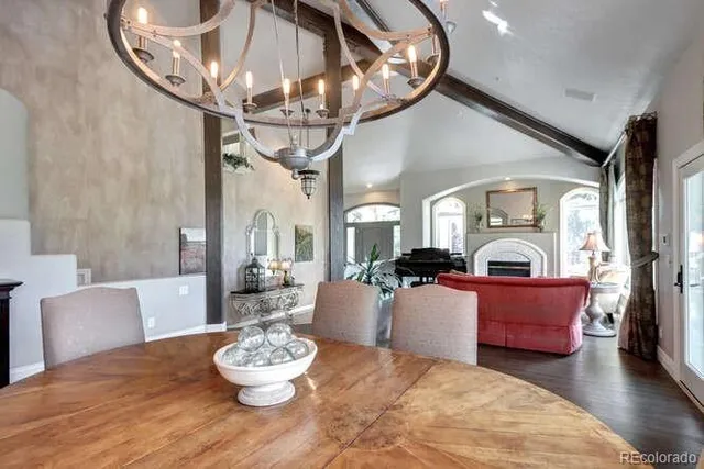 a living room with furniture chandelier and a dining table with wooden floor