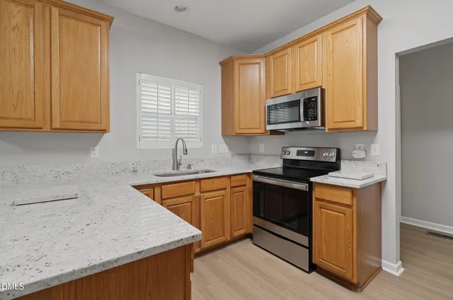 a kitchen with stainless steel appliances granite countertop wooden cabinets a stove top oven a sink and dishwasher with wooden floor