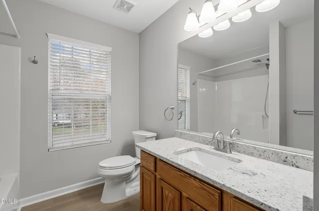 a bathroom with a granite countertop sink a toilet and a mirror