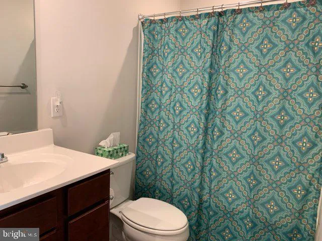 a bathroom with a granite countertop sink and a toilet