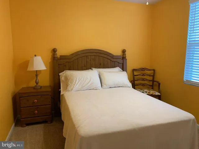 a bedroom with a bed and a lamp on dresser
