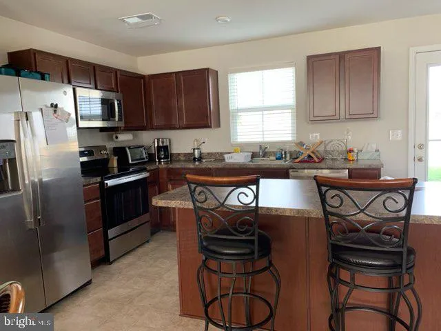 a kitchen with stainless steel appliances granite countertop a sink a stove a refrigerator cabinets and a dining table