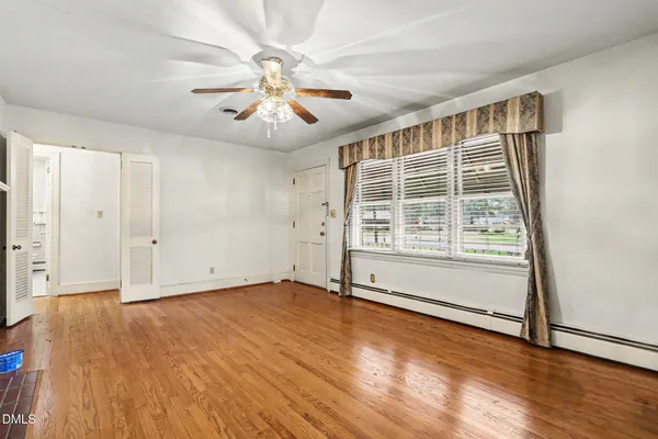 an empty room with wooden floor and windows