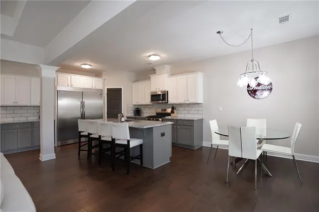 a kitchen with a dining table chairs appliances and cabinets