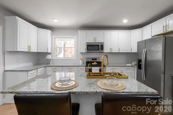 a kitchen with stainless steel appliances granite countertop a sink a stove and a refrigerator