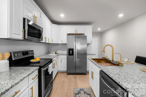 a kitchen with stainless steel appliances granite countertop a sink a stove and a refrigerator