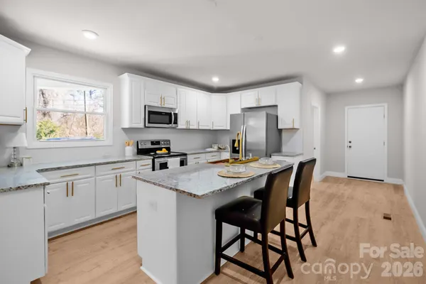 a kitchen with a stove a sink a microwave a dining table and chairs