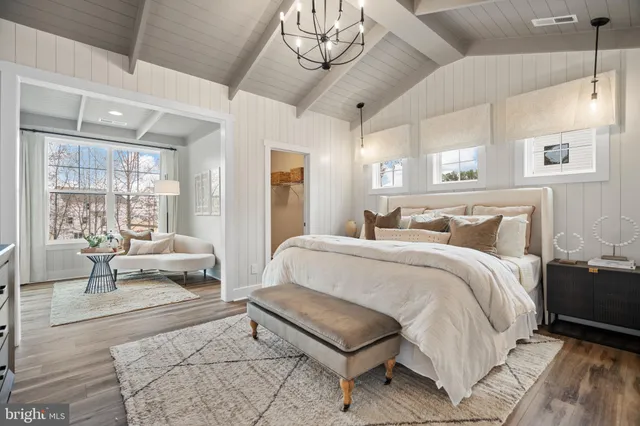 a spacious bedroom with a bed a chandelier and couches