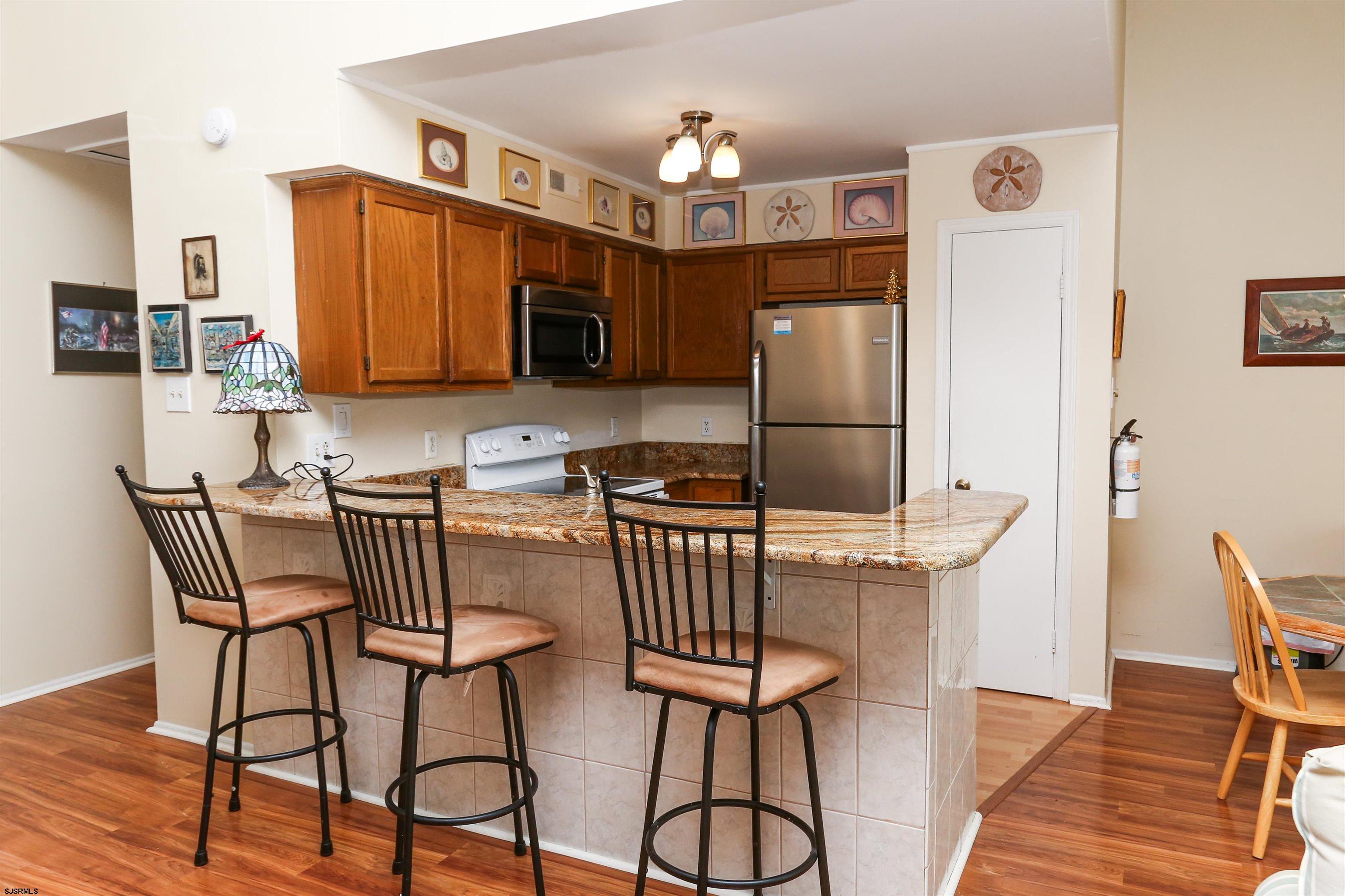 340 Seashell Lane Brigantine, NJ 08203 - Photo 13 of 29 a kitchen with stainless steel appliances granite countertop a dining table chairs refrigerator and microwave