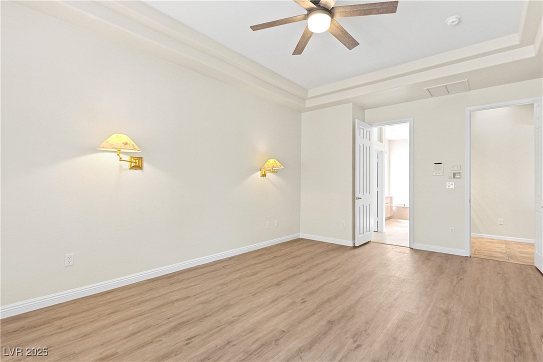 10548 Findlay Avenue Las Vegas, NV 89134 - Photo 22 of 27 Spare room featuring a tray ceiling, light wood finished floors, and ceiling fan