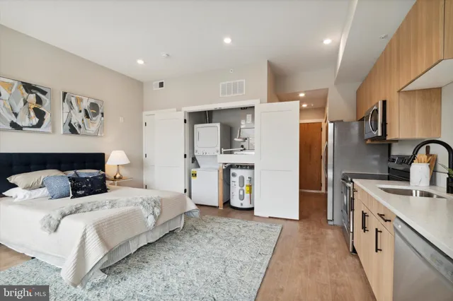 a large bedroom with a bed a refrigerator and cabinets