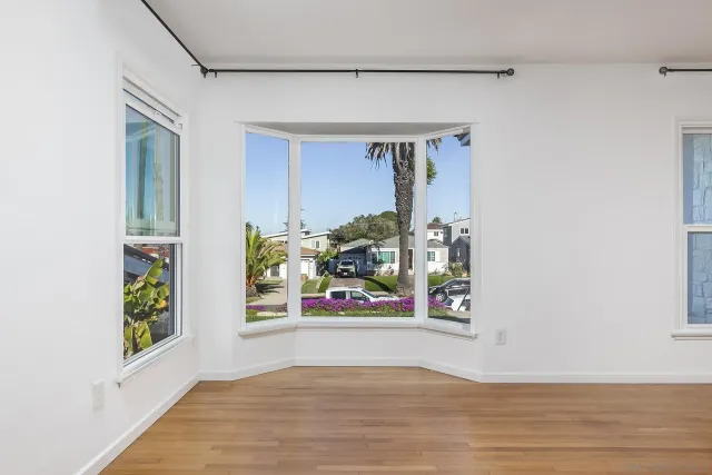 a view of an empty room with wooden floor and a bathroom