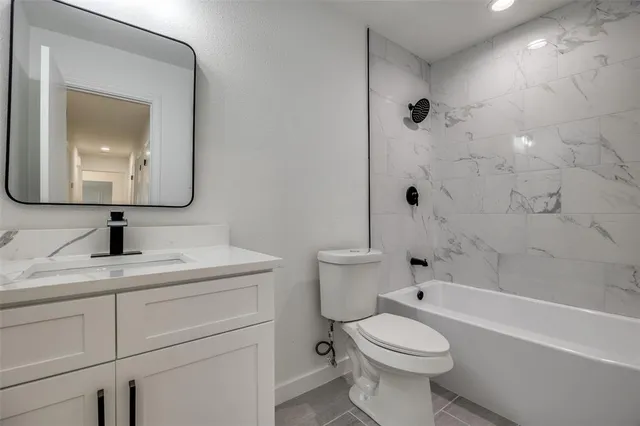 a bathroom with a toilet sink vanity tub and mirror