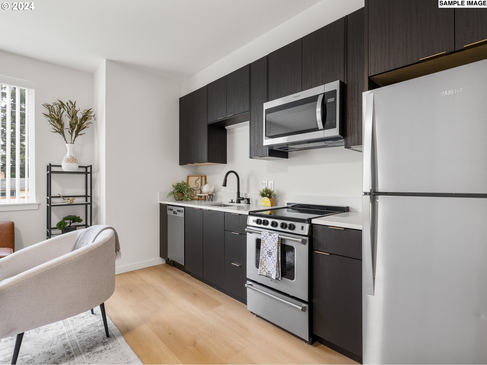 10985 East Burnside Street, Unit 24 Portland, OR 97216 - Photo 5 of 9 a kitchen with stainless steel appliances granite countertop a stove a microwave and a refrigerator