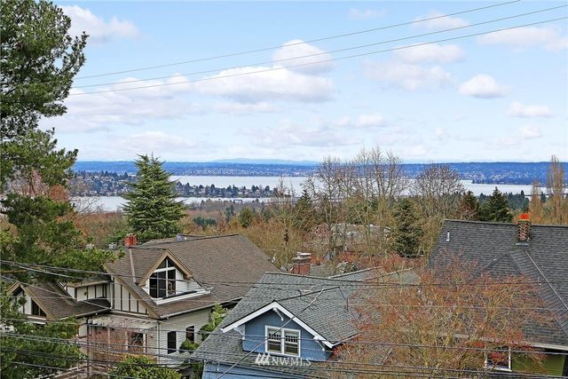a view of a big house with a big yard and large trees