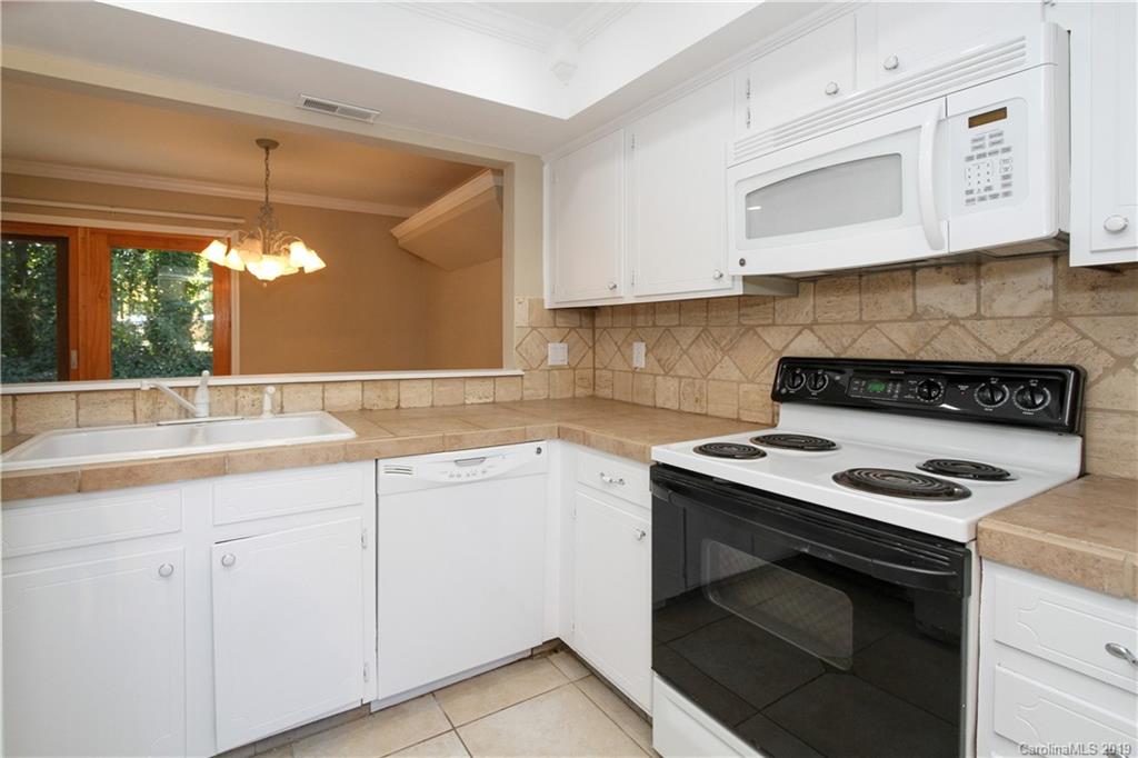 7825 Renaissance Court, Unit B Charlotte, NC 28226 - Photo 6 of 21 a kitchen with granite countertop a stove sink and cabinets