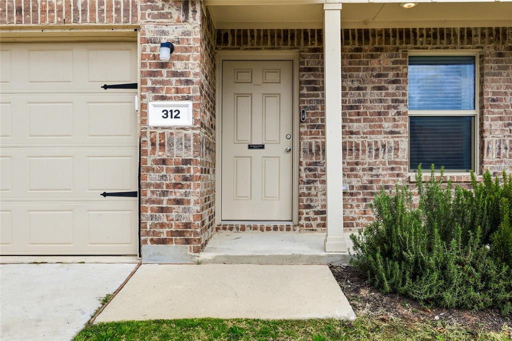 312 Ranchito Pass Fort Worth, TX 76052 - Photo 4 of 30 Doorway to property featuring brick siding, covered porch, and a garage