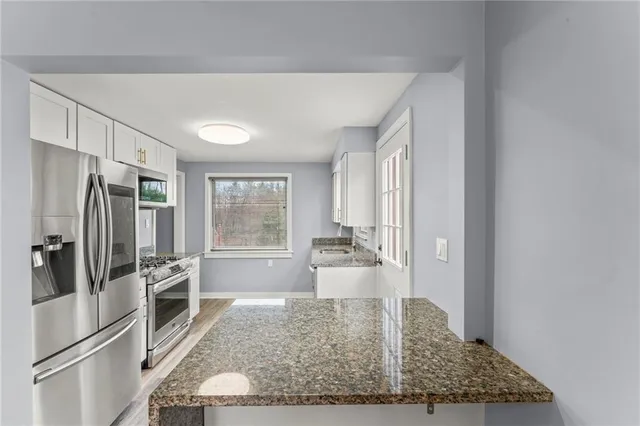 a kitchen with stainless steel appliances granite countertop a refrigerator a stove a sink and a window