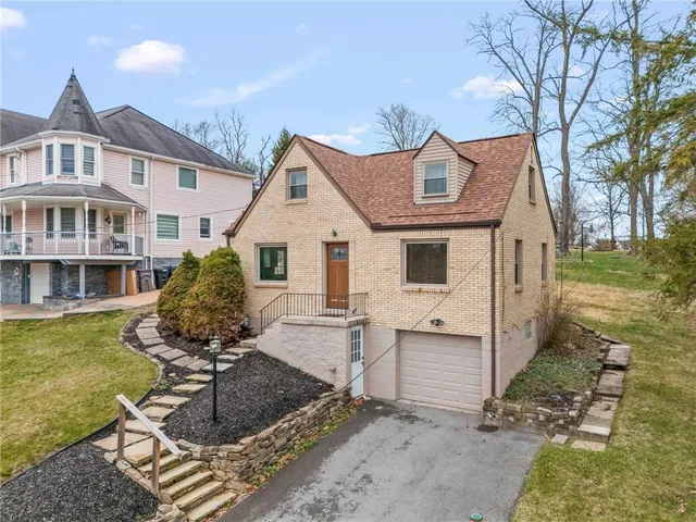 a view of a white house with a yard table and chairs