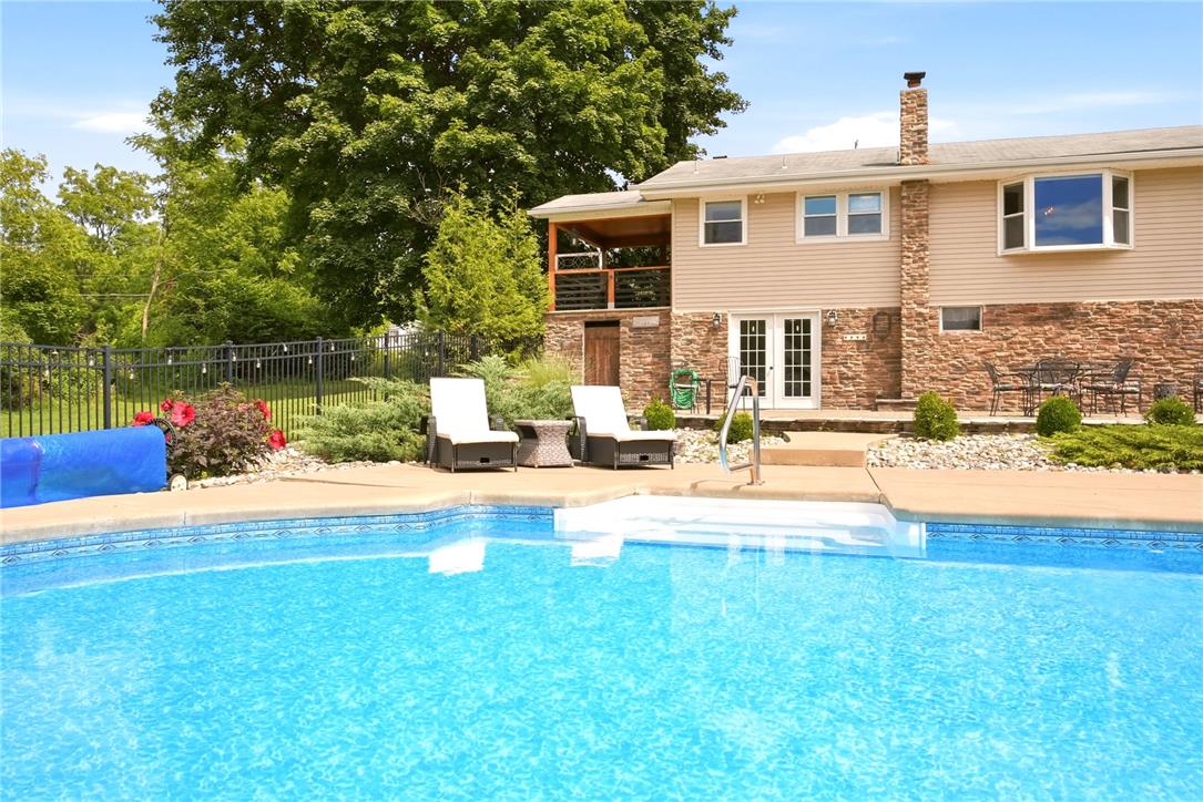 463 North Penn Dixie Road Bath, PA 18014 - Photo 63 of 86 An inviting backyard features a sparkling blue pool, complemented by a stone-faced house with a charming bay window.