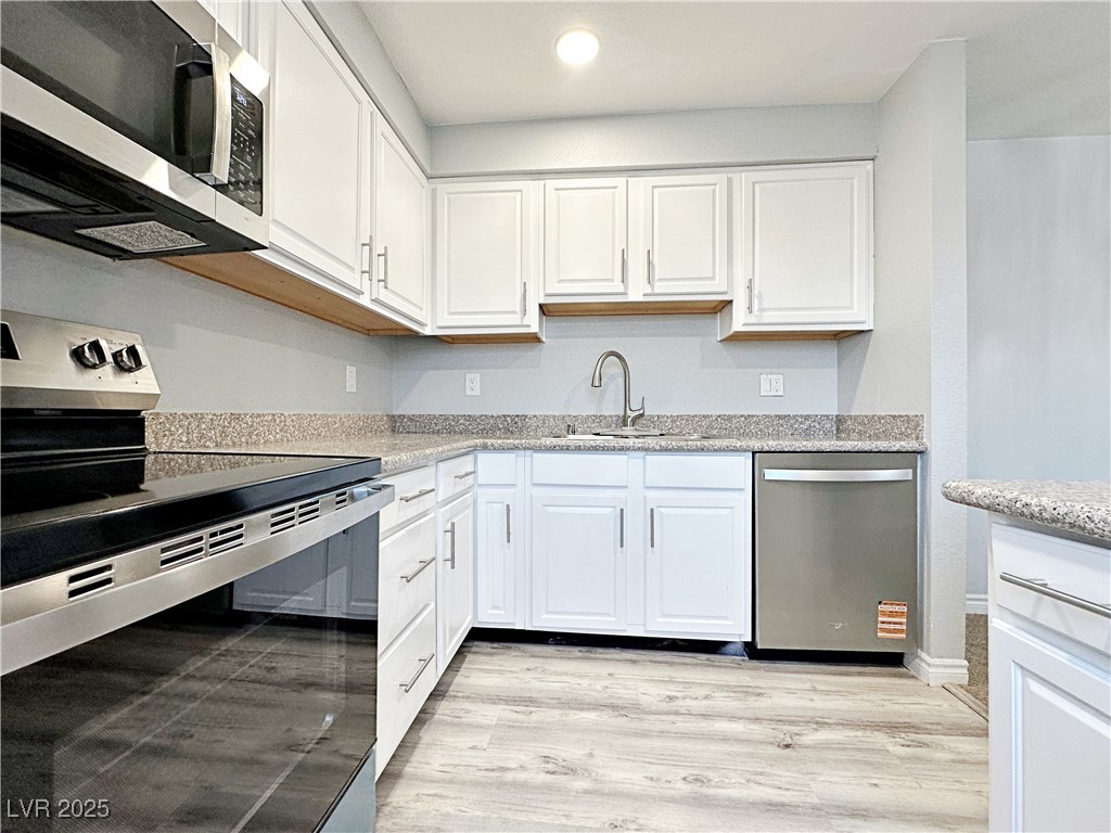 Kitchen with appliances with stainless steel finishes, white cabinets, and recessed lighting