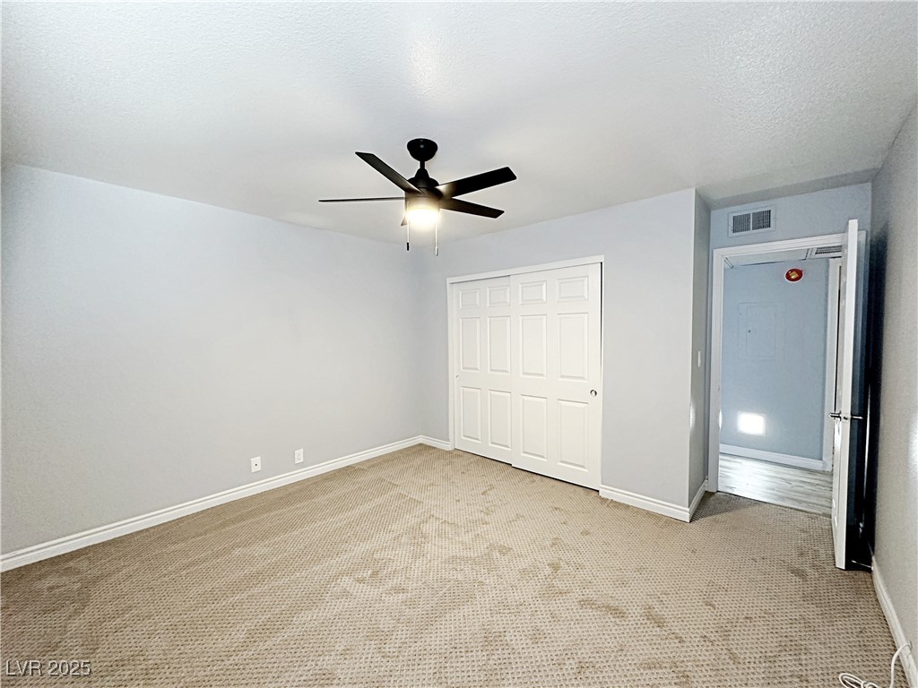 5080 Indian River Drive, Unit 400 Las Vegas, NV 89103 - Photo 16 of 29 Unfurnished bedroom featuring a textured ceiling, carpet flooring, a closet, and a ceiling fan