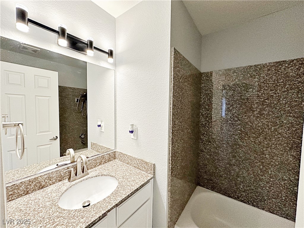 5080 Indian River Drive, Unit 400 Las Vegas, NV 89103 - Photo 17 of 29 Full bath featuring a textured wall, vanity, and bathing tub / shower combination