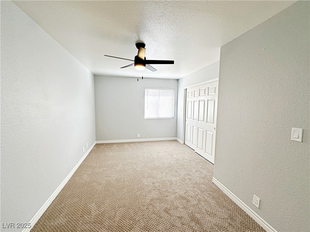 5080 Indian River Drive, Unit 400 Las Vegas, NV 89103 - Photo 19 of 29 Unfurnished bedroom with a textured wall, light carpet, a textured ceiling, a closet, and a ceiling fan
