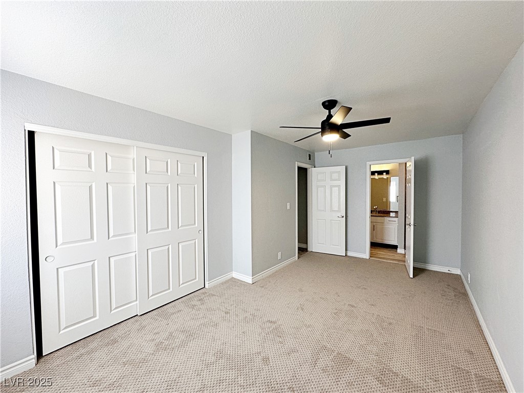 5080 Indian River Drive, Unit 400 Las Vegas, NV 89103 - Photo 20 of 29 Unfurnished bedroom featuring carpet, a closet, connected bathroom, and ceiling fan