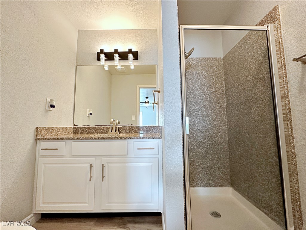 5080 Indian River Drive, Unit 400 Las Vegas, NV 89103 - Photo 21 of 29 Bathroom with a textured wall, vanity, and a stall shower