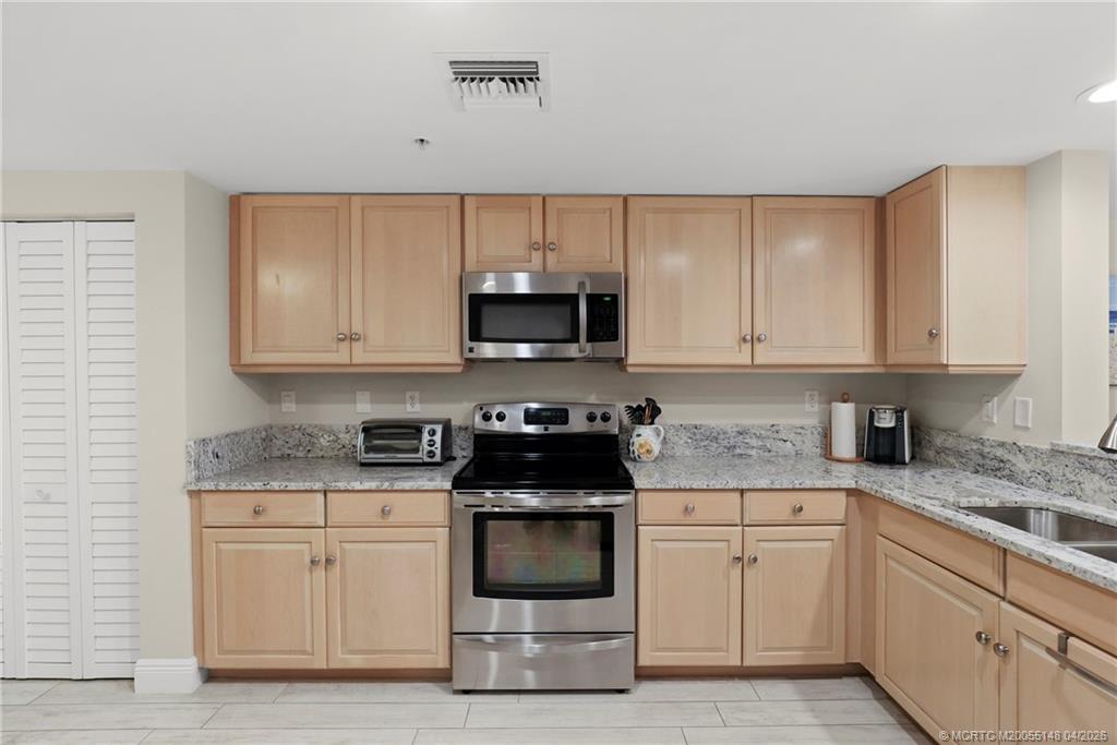 579 Northeast Plantation Road, Unit N107 Jensen Beach, FL 34957 - Photo 15 of 44 a kitchen with granite countertop white cabinets and stainless steel appliances