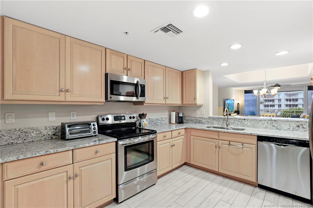 579 Northeast Plantation Road, Unit N107 Jensen Beach, FL 34957 - Photo 16 of 44 a kitchen with granite countertop white cabinets and white appliances