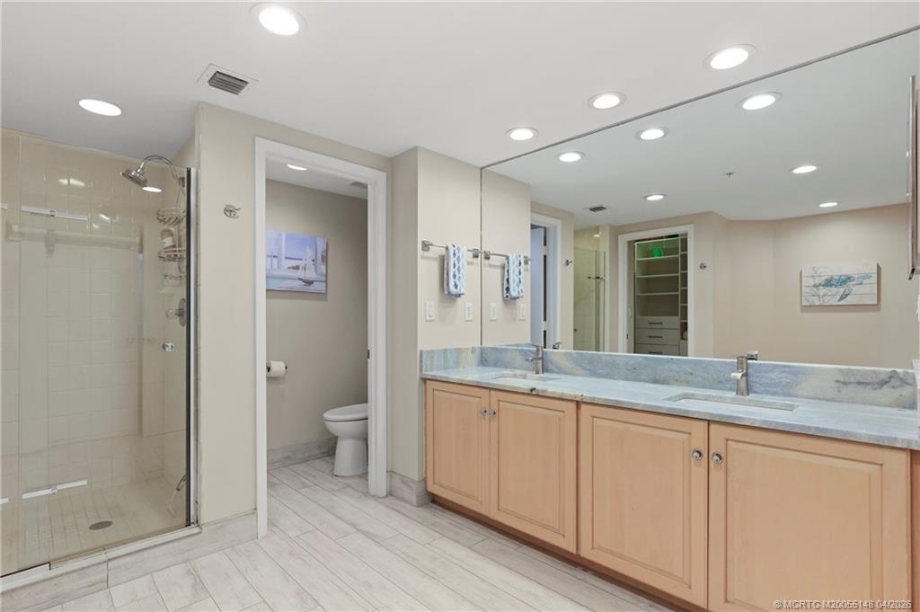 579 Northeast Plantation Road, Unit N107 Jensen Beach, FL 34957 - Photo 31 of 44 a bathroom with a granite countertop double vanity sink a mirror and a