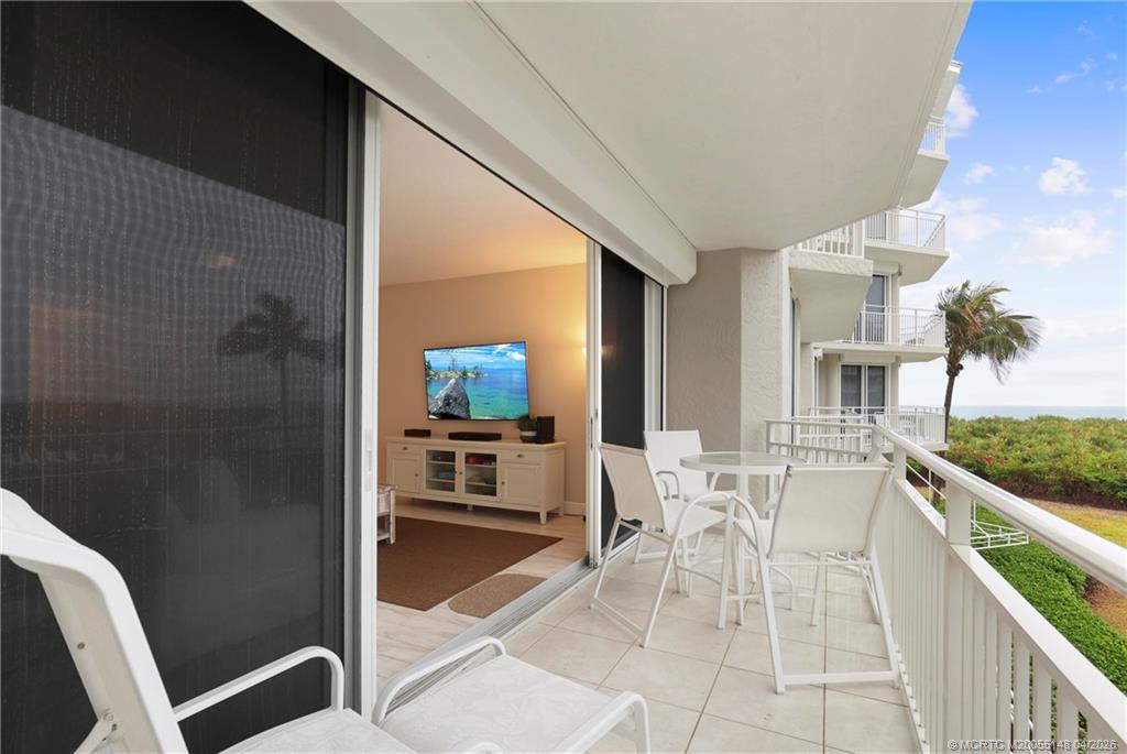 579 Northeast Plantation Road, Unit N107 Jensen Beach, FL 34957 - Photo 37 of 44 a living room with furniture a flat screen tv and a floor to ceiling window