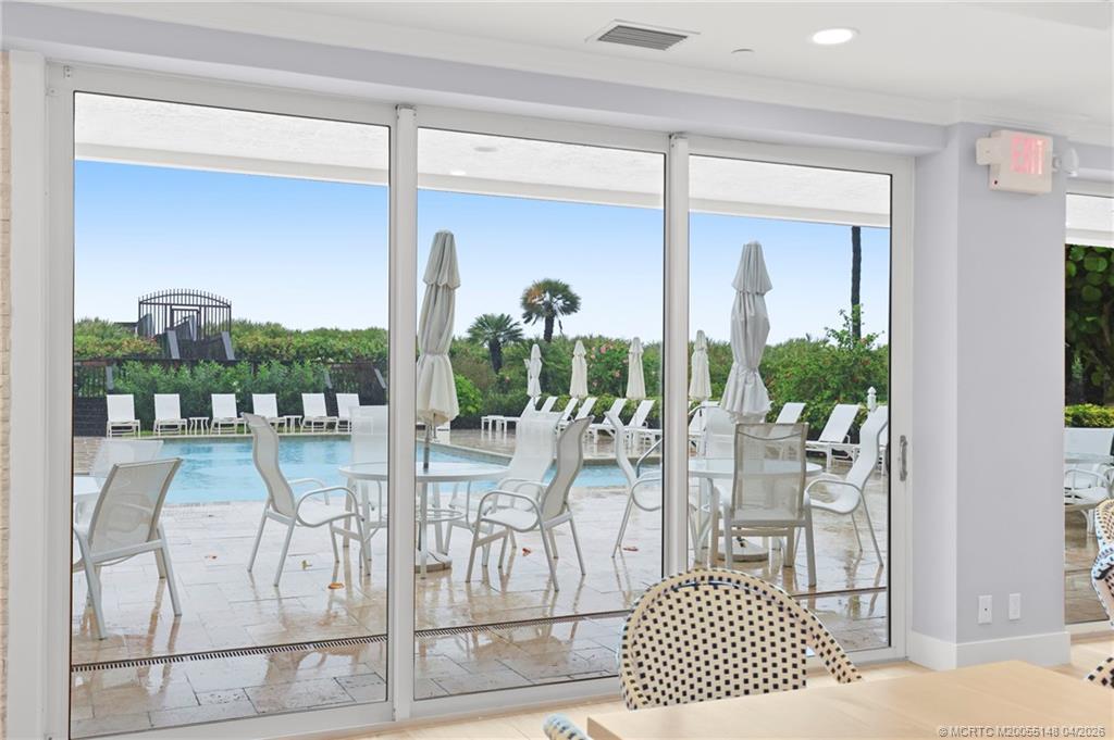 579 Northeast Plantation Road, Unit N107 Jensen Beach, FL 34957 - Photo 42 of 44 a view of a dining room with furniture wooden floor and floor to ceiling window
