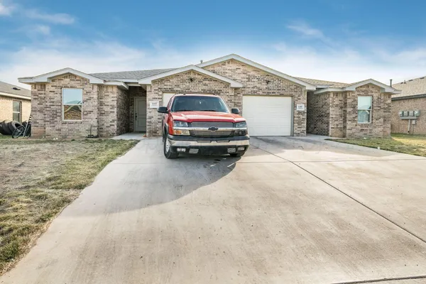 a front view of a house with a yard and parking space