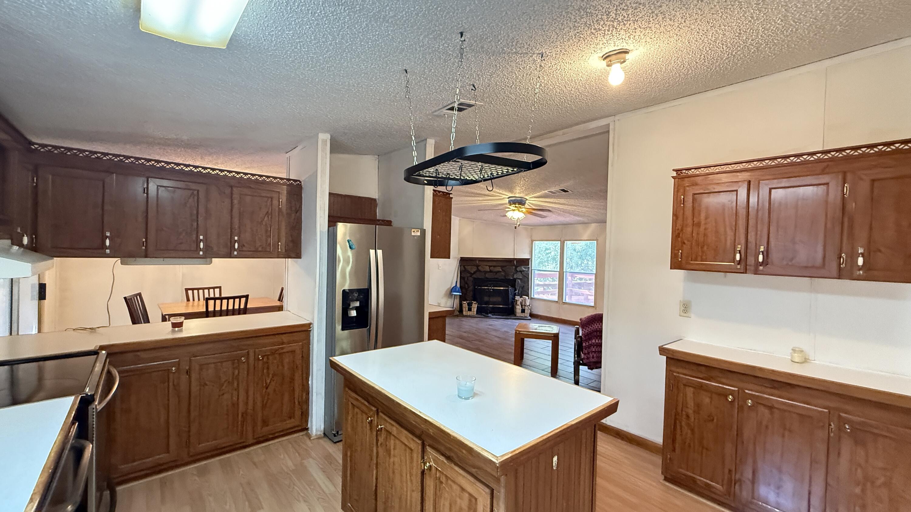 5243 Morris Street Crestview, FL 32539 - Photo 7 of 25 a kitchen with a refrigerator a sink dishwasher and wooden cabinets with wooden floor