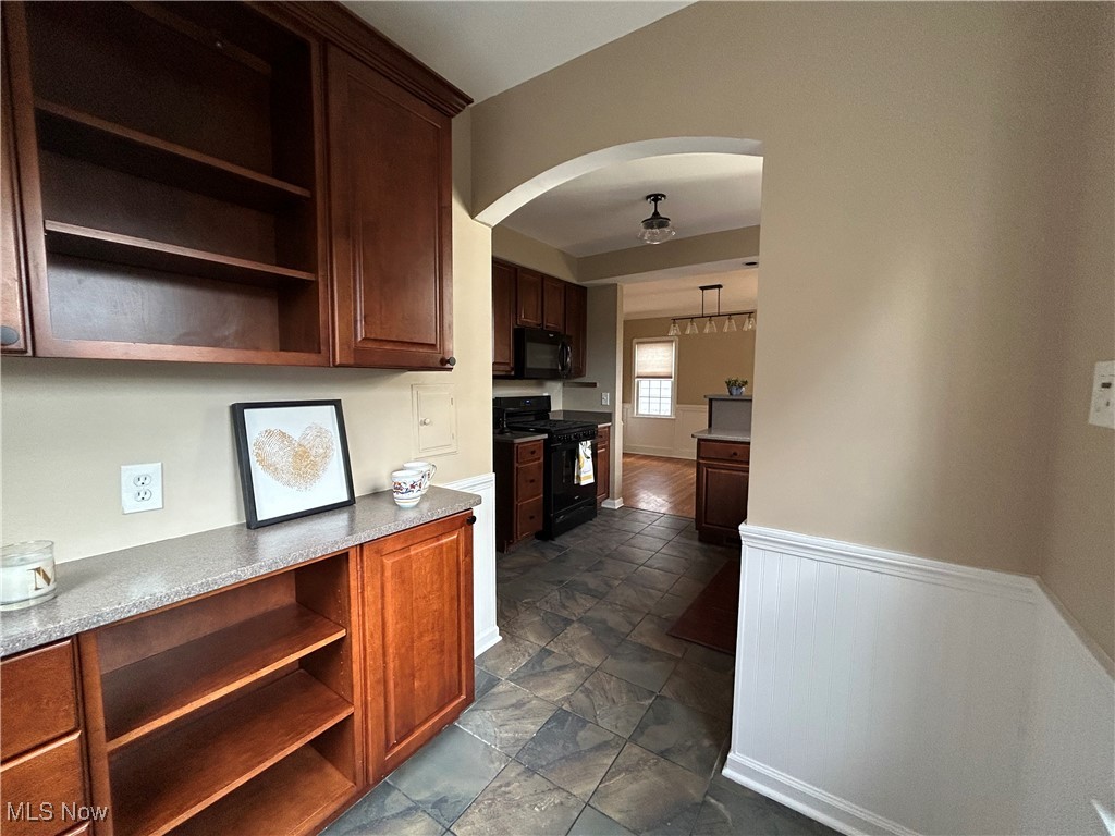 3589 Strandhill Road Beachwood, OH 44122 - Photo 22 of 23 Kitchen featuring open shelves, arched walkways, black appliances, a wainscoted wall, and dark brown cabinetry