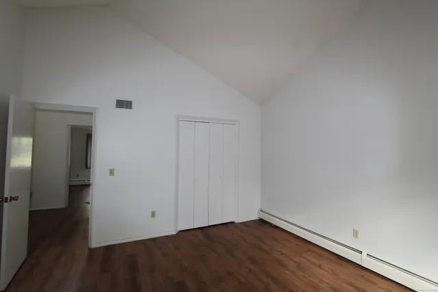 a view of an empty room with wooden floor and closet