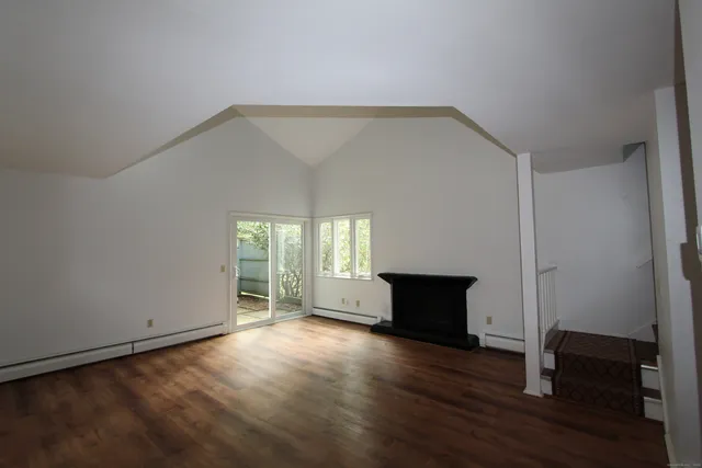 an empty room with wooden floor a fireplace and windows