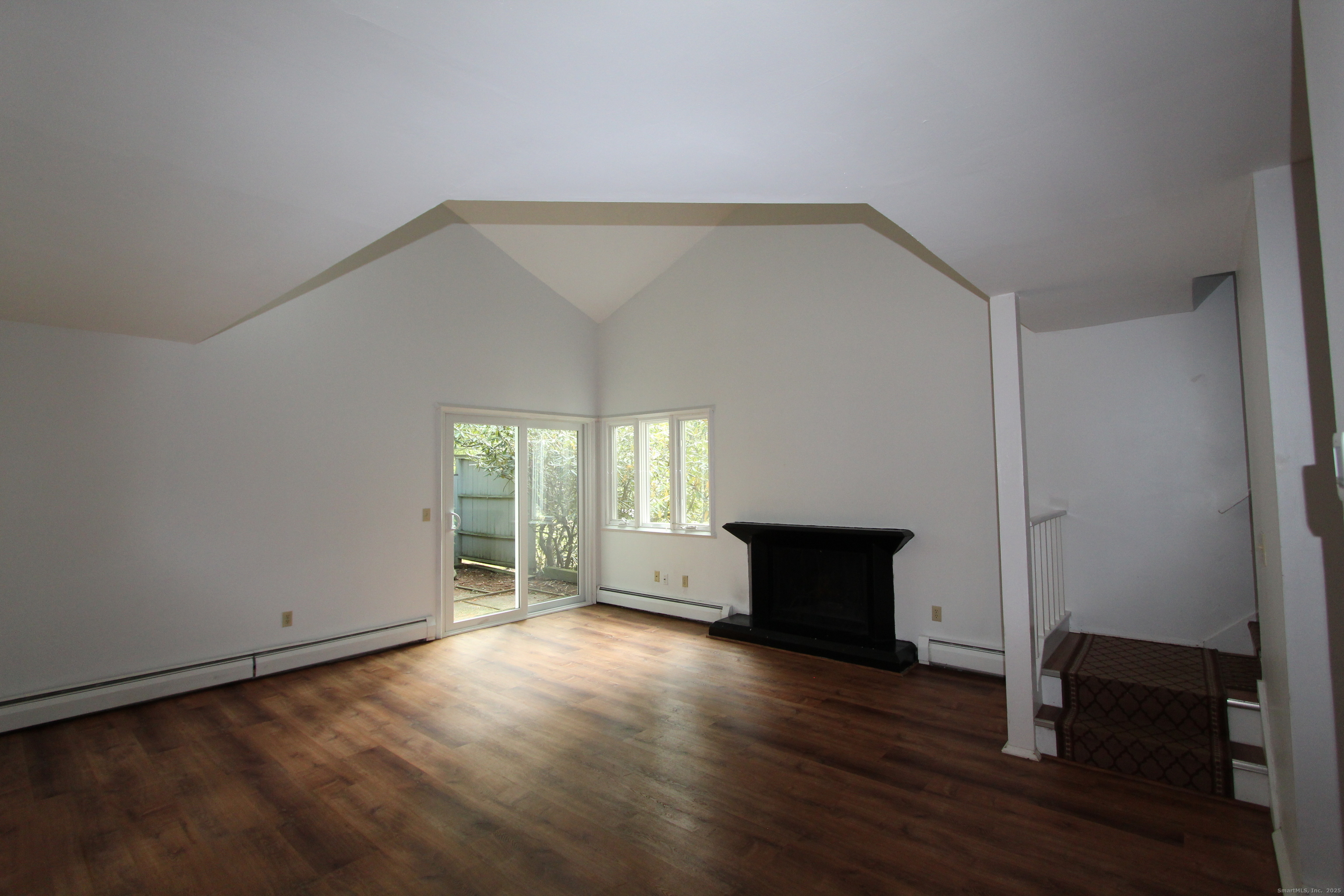 6 Lyle Court, Unit C Farmington, CT 06032 - Photo 5 of 34 an empty room with wooden floor a fireplace and windows