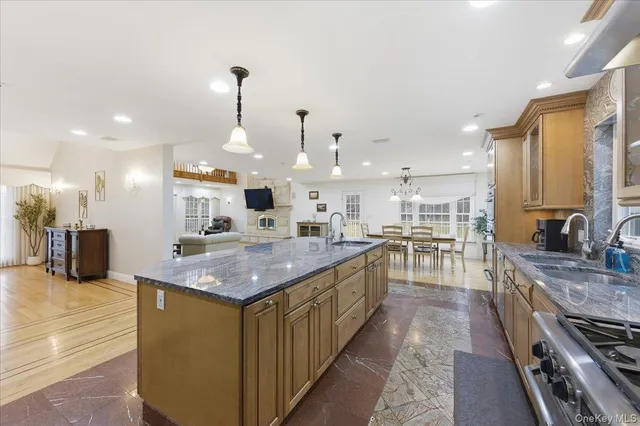 a kitchen with stainless steel appliances granite countertop a sink a stove and a wooden floors