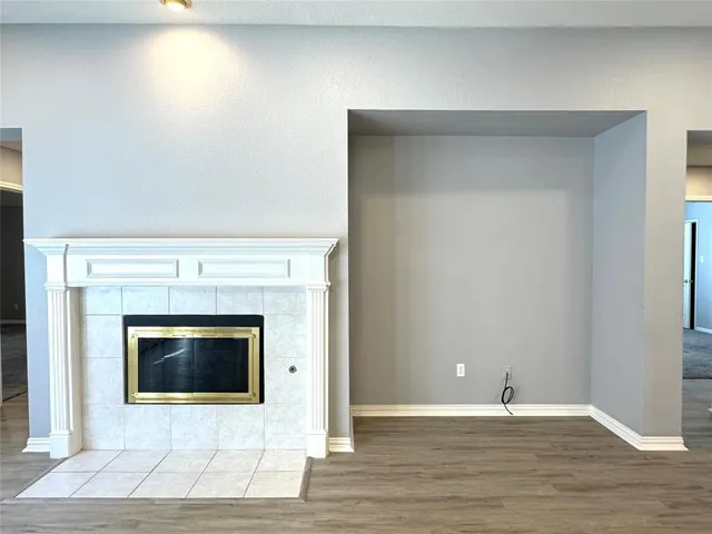 a view of an empty room with wooden floor and fireplace
